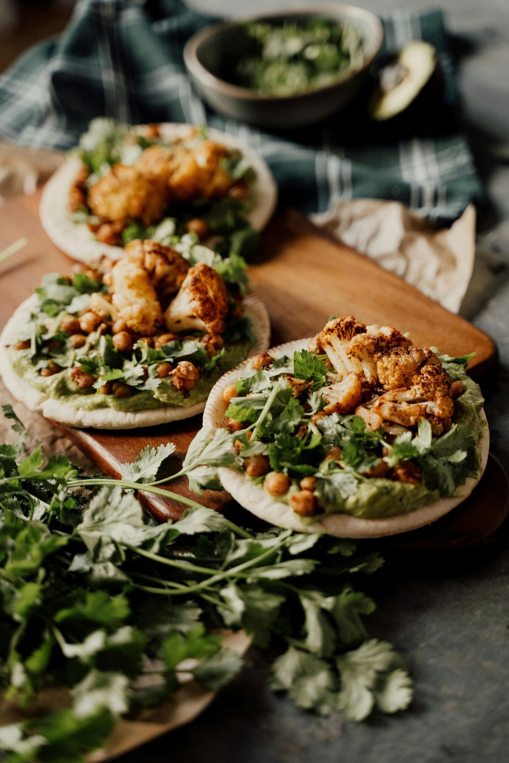 3 plates of cauliflower tacos with lots of veggies and herbs