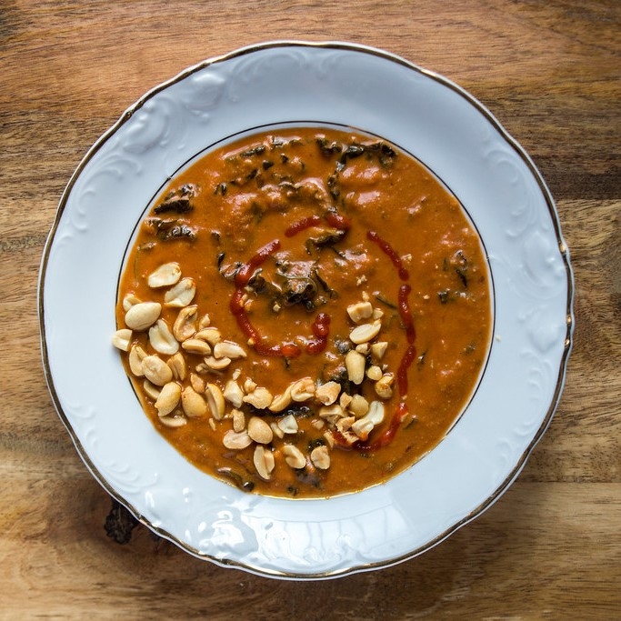 close up of african peanut stew with peanut garnish in a white bowl