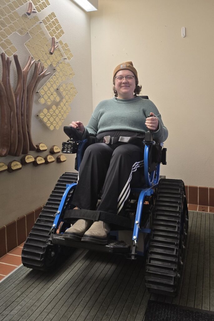 a woman sitting in a bright blue trackchair in the Riveredge visitor center foyer