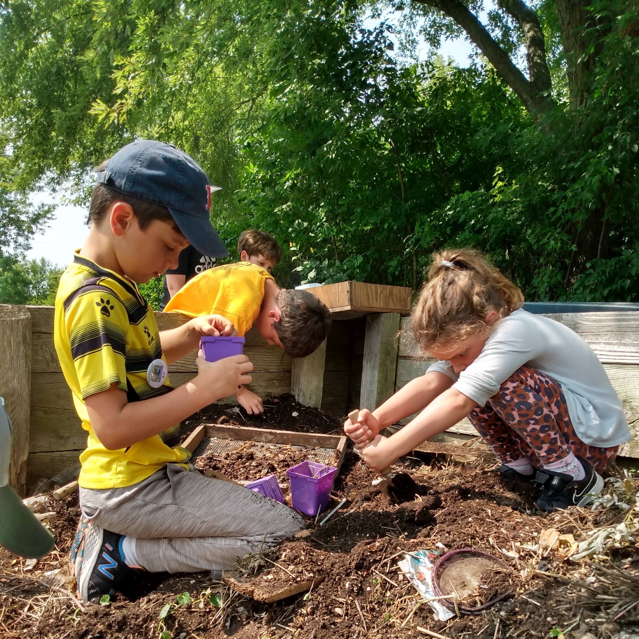 2 young kids digging the in the dirt of the Riveredge garden