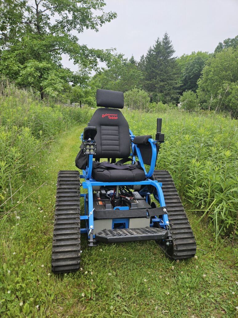 the new blue Riveredge Trackchair on a grassy trail on a summer day