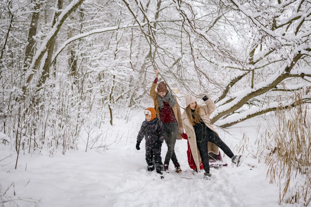 a family with 2 parents and 2 kids hiking on a snowy winter forest trail